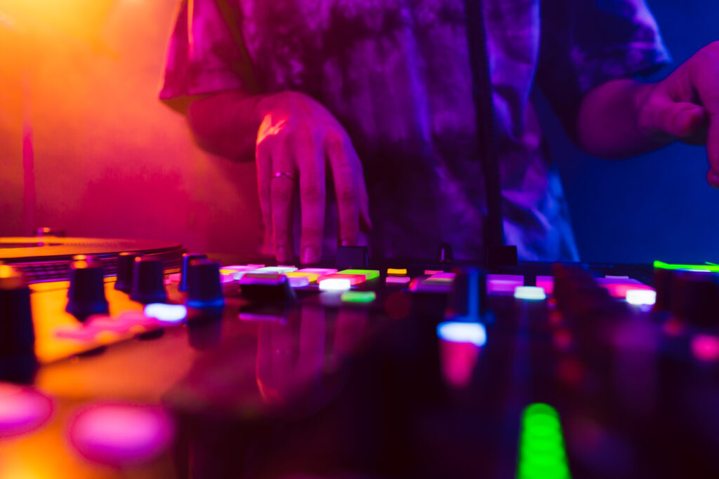 Close up of DJ hands on dj console mixer during concert in the night club